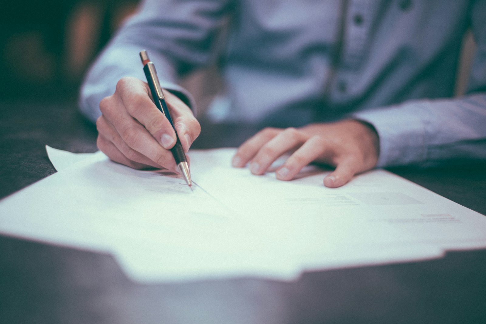 A person reviewing and signing paperwork at a desk